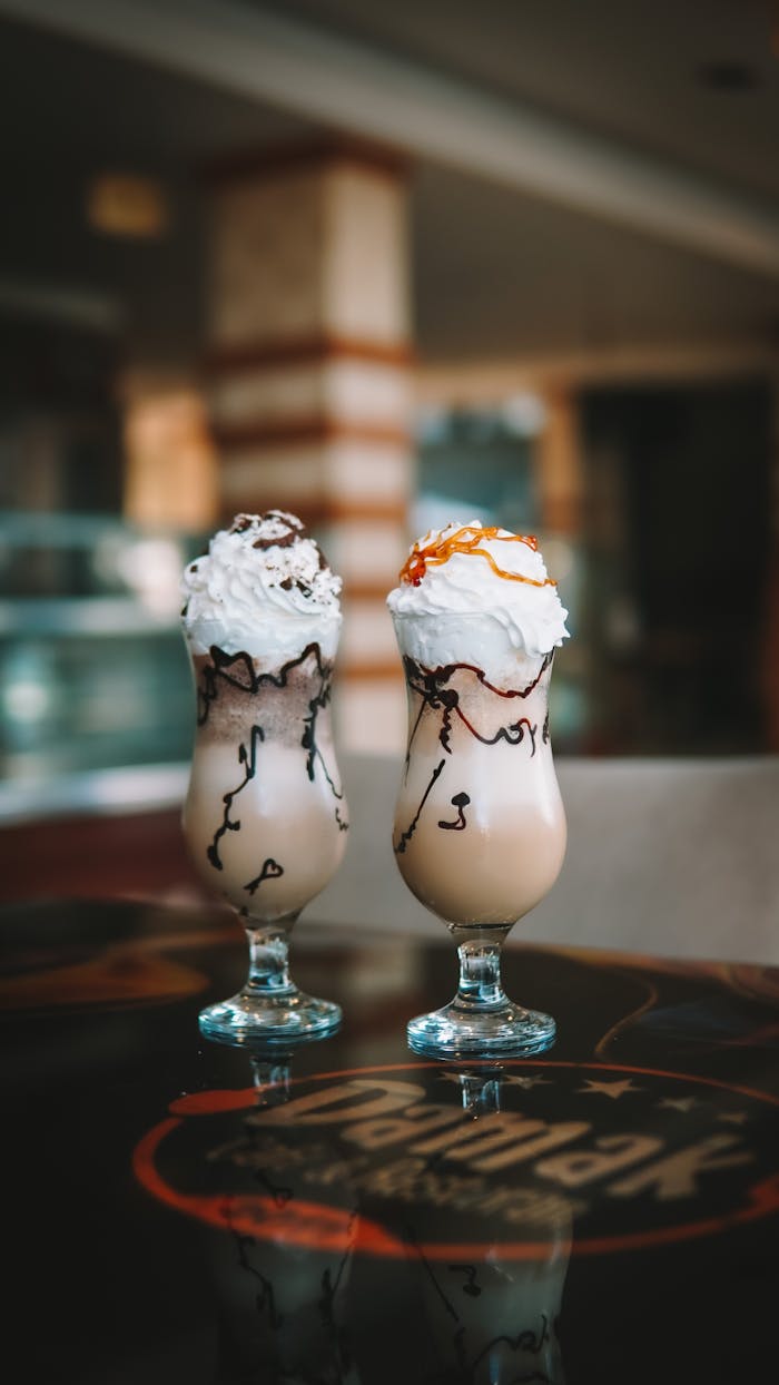 client-stories-img Indulgent milkshakes adorned with whipped cream and drizzled toppings on a cafe table.
