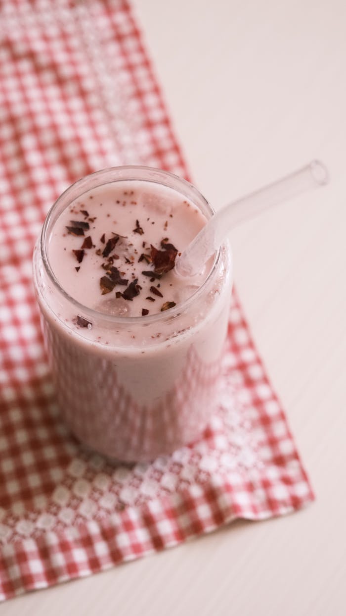my-qualifications Refreshing strawberry shake with chocolate shavings on a checked tablecloth, perfect for summer.