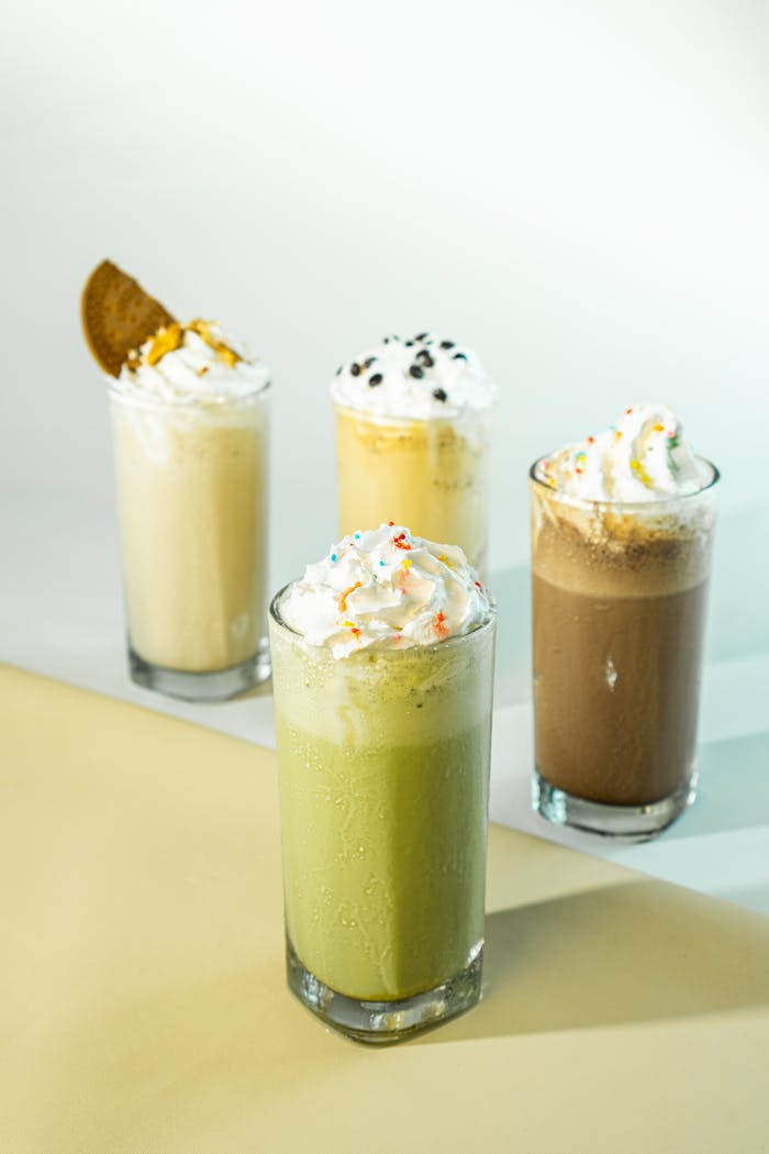 Colorful milkshakes with whipped cream and toppings on a pastel background. Perfect for summer refreshment.