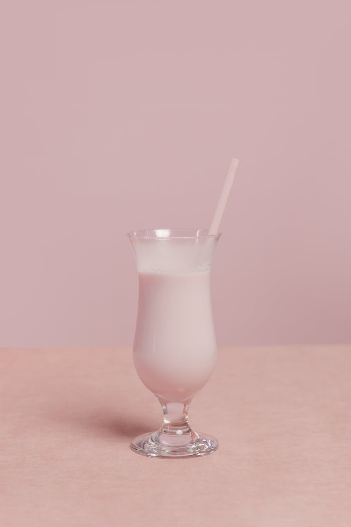 my-path A creamy pink milkshake in a clear glass with a straw, set against a soft pink backdrop.