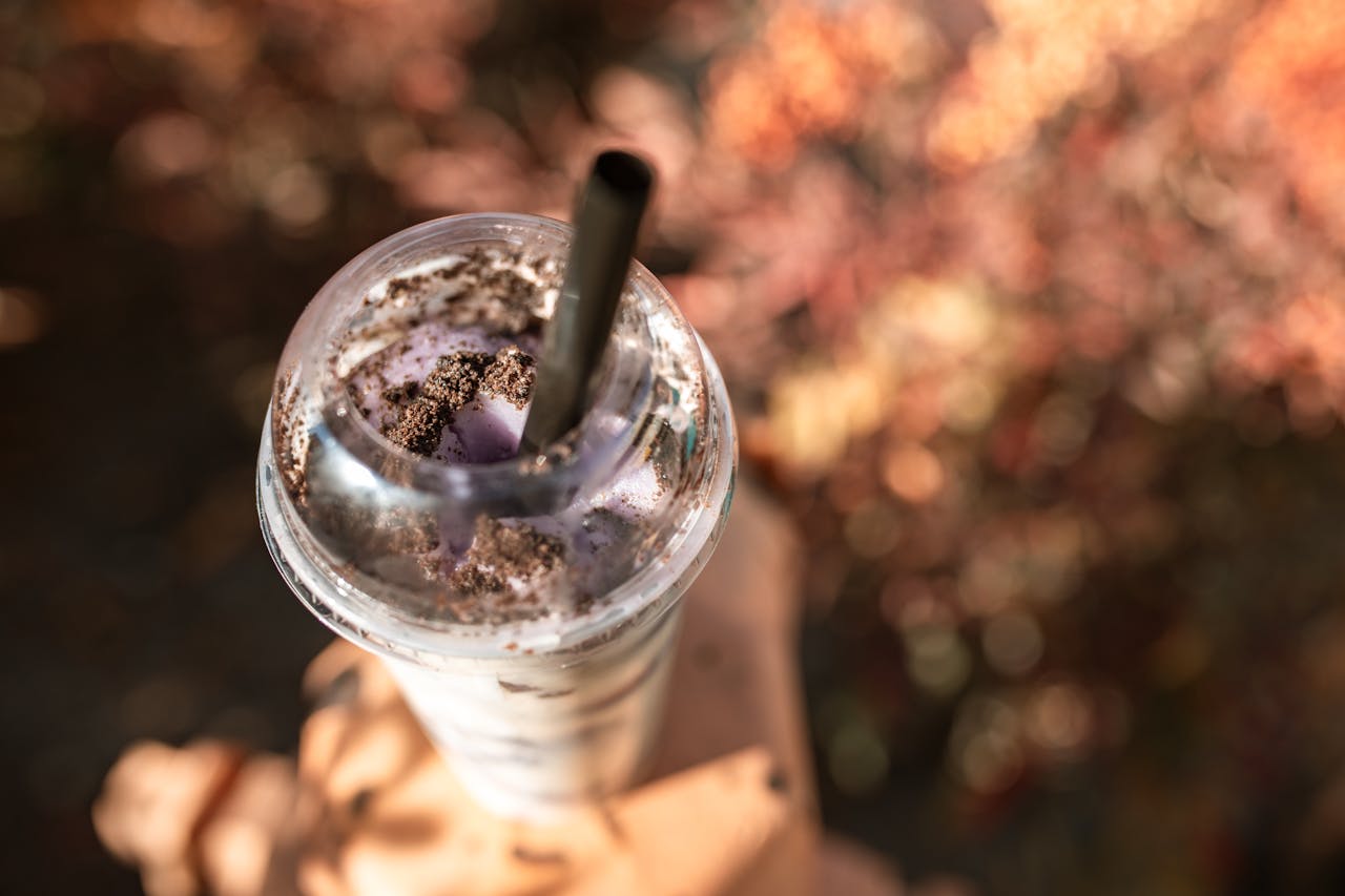 who-we-are An enticing close-up of an Oreo milkshake topped with cookies in a plastic cup with straw.